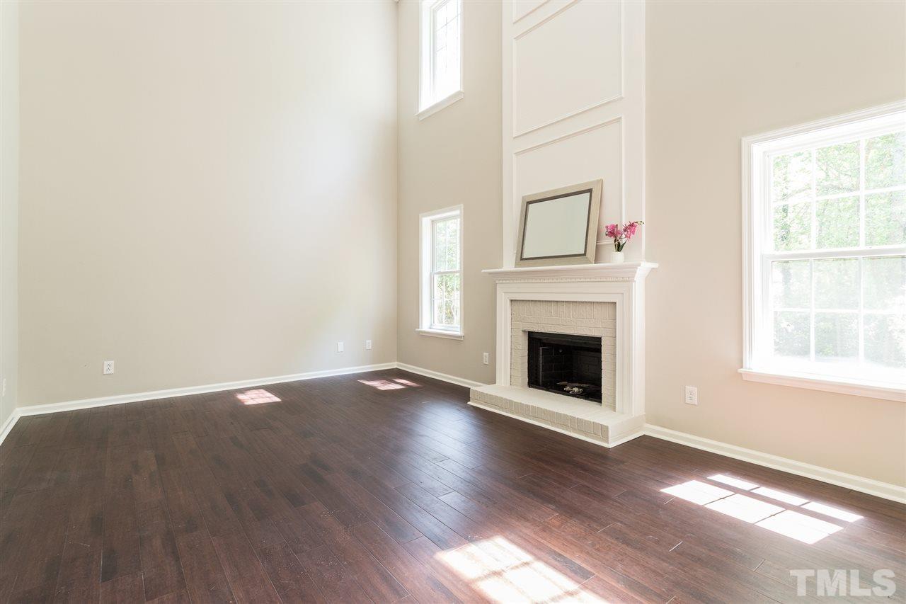 4628 Drewbridge Way Raleigh, NC 27604 - Photo 9 of 21 an empty room with wooden floor fireplace and windows