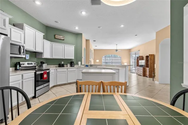 a kitchen with stainless steel appliances granite countertop a refrigerator a stove and white cabinets with wooden floor