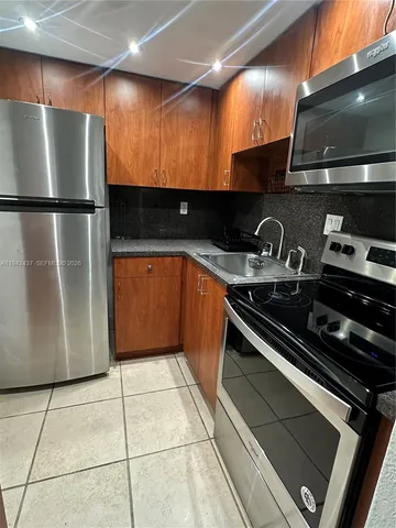 a kitchen with stainless steel appliances granite countertop a refrigerator and a stove top oven