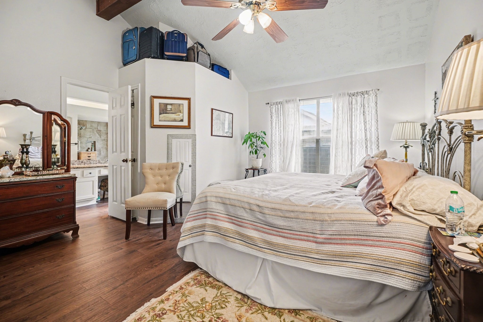 16810 Finewood Way Houston, TX 77058 - Photo 15 of 23 Spacious primary bedroom featuring a tall vaulted ceiling with an exposed wood beam, laminate wood flooring, fresh neutral paint, large windows, a walk-in closet, and extra linen closet behind the bathroom door.