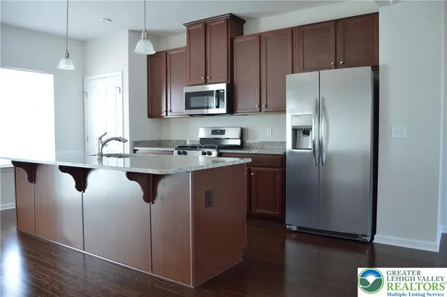 a kitchen with stainless steel appliances granite countertop a refrigerator a sink a stove a microwave and wooden floors