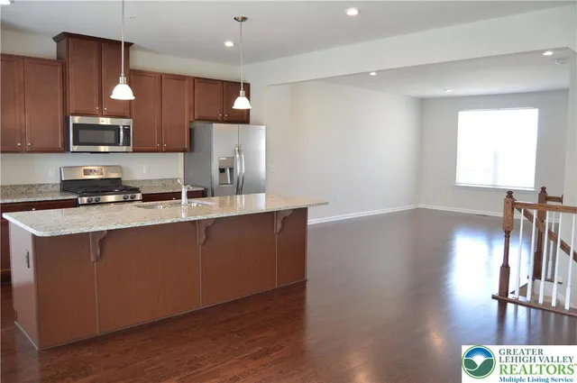 a kitchen with stainless steel appliances granite countertop a refrigerator a sink dishwasher a stove and a oven with wooden floor