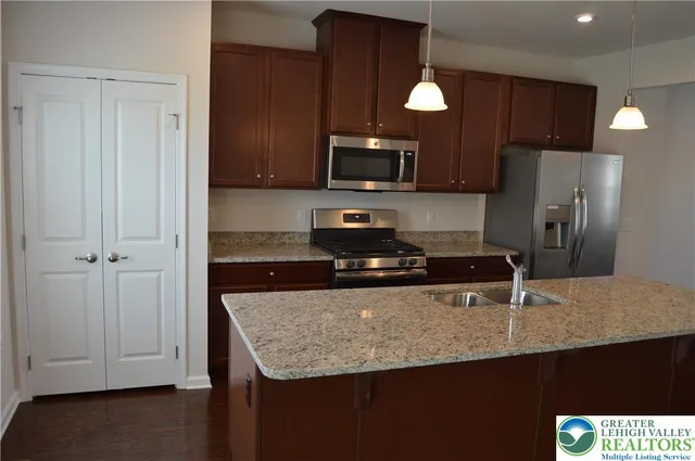 a kitchen with granite countertop a refrigerator a sink and a stove