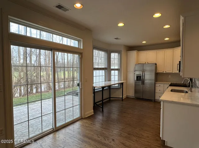 a kitchen with refrigerator and wooden floor