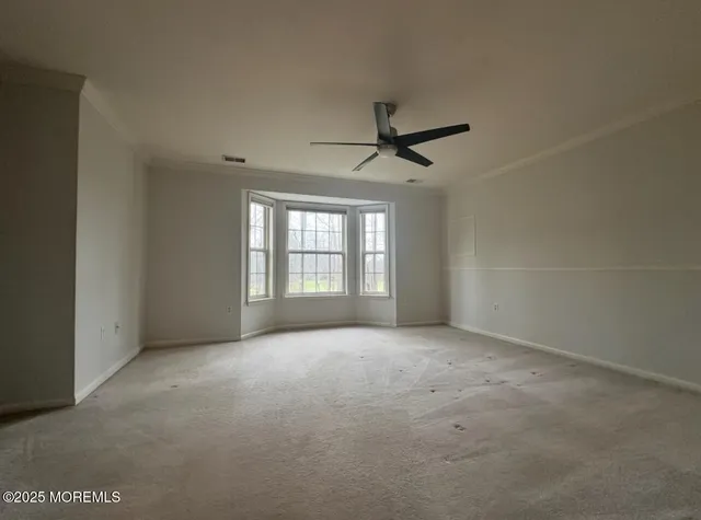 an empty room with windows and ceiling fan