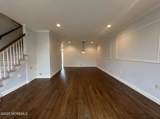 a view of an empty room with wooden floor and stairs