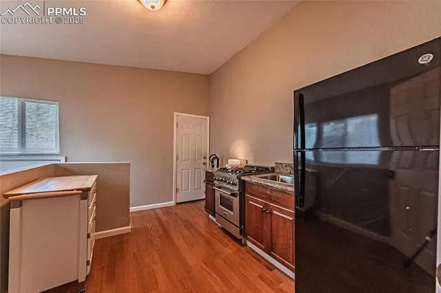 a kitchen with granite countertop a refrigerator stove and wooden floor