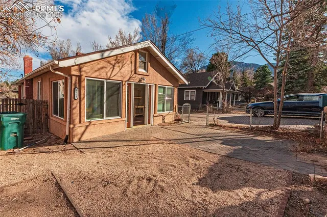 a backyard of a house with large trees and wooden fence