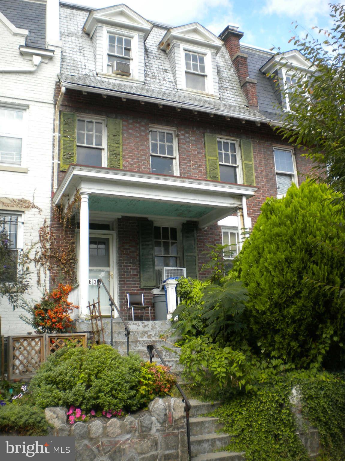 a front view of a house with plants and entryway