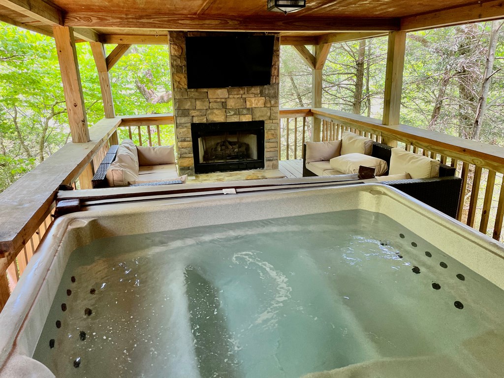 586 Newport Road Blue Ridge, GA 30513 - Photo 11 of 38 a living room with a fireplace and a flat tv screen next to a large window