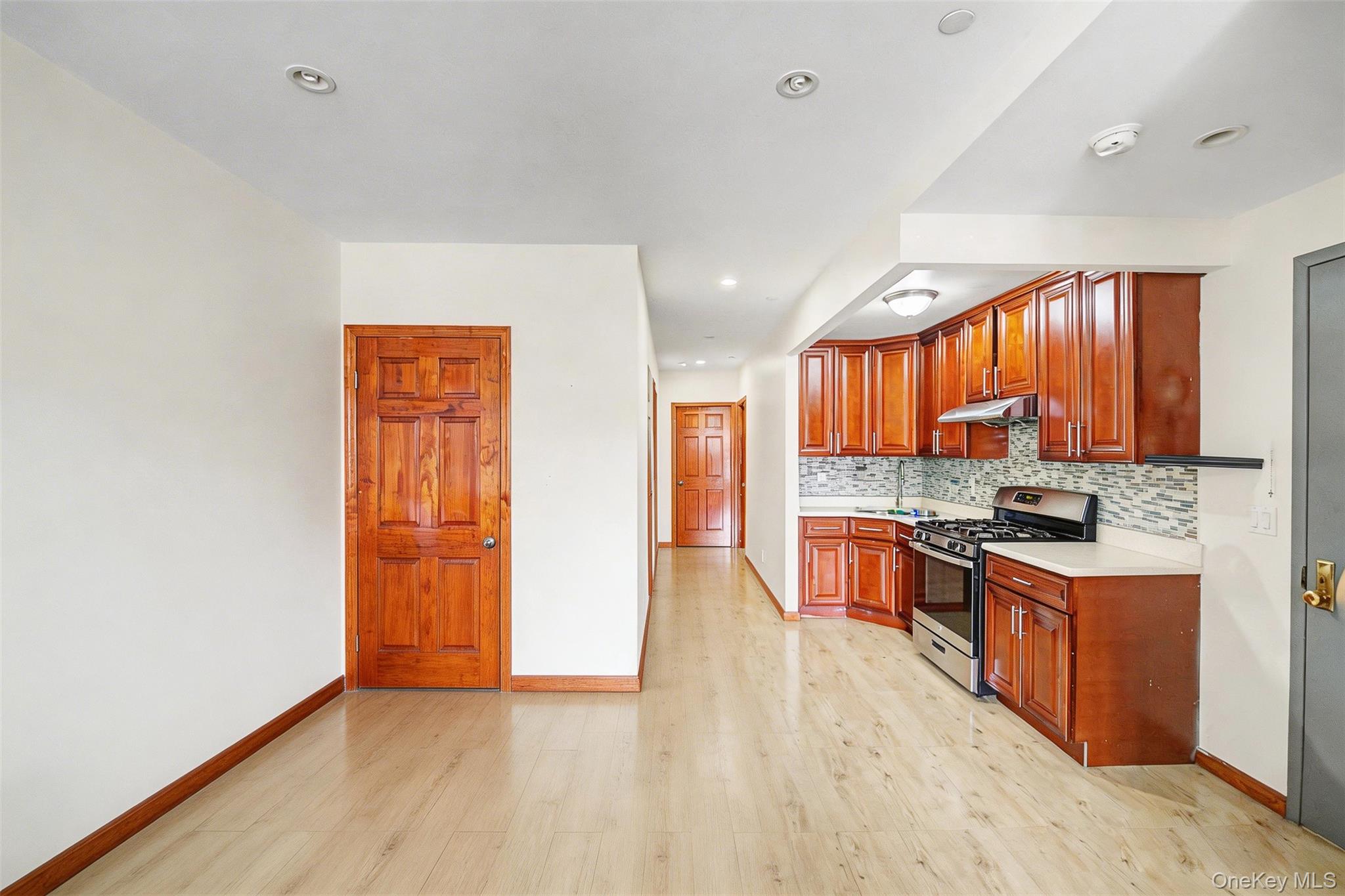 57-50 Granger Street, Unit 3A Queens, NY 11368 - Photo 5 of 20 Kitchen with light countertops, stainless steel range with gas cooktop, light wood-type flooring, backsplash, and wood finish cabinetry