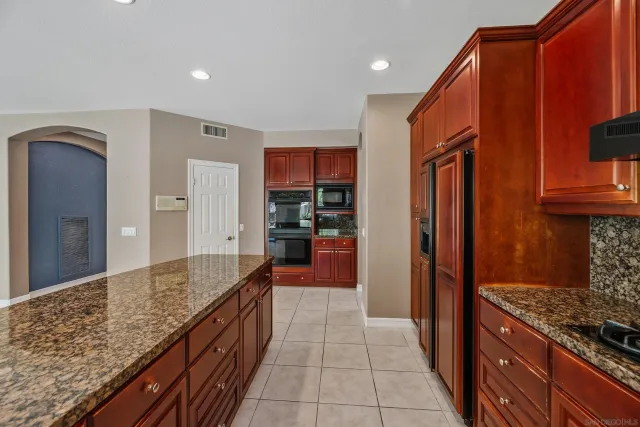a kitchen with stainless steel appliances granite countertop wooden cabinets a dining table and chairs