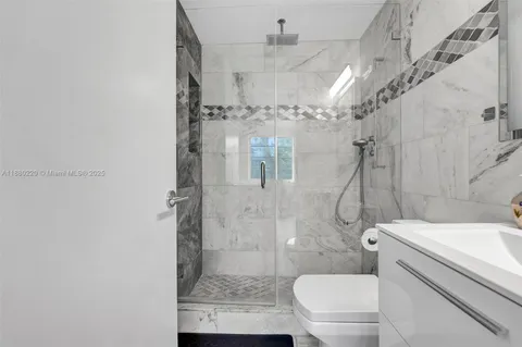 a bathroom with a granite countertop shower a toilet and a shower