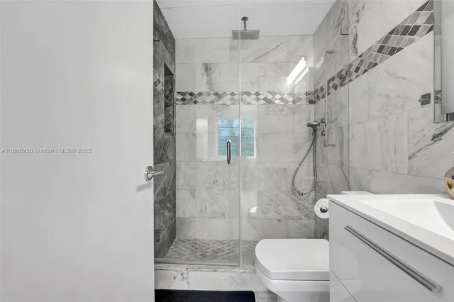 a bathroom with a granite countertop shower a toilet and a shower