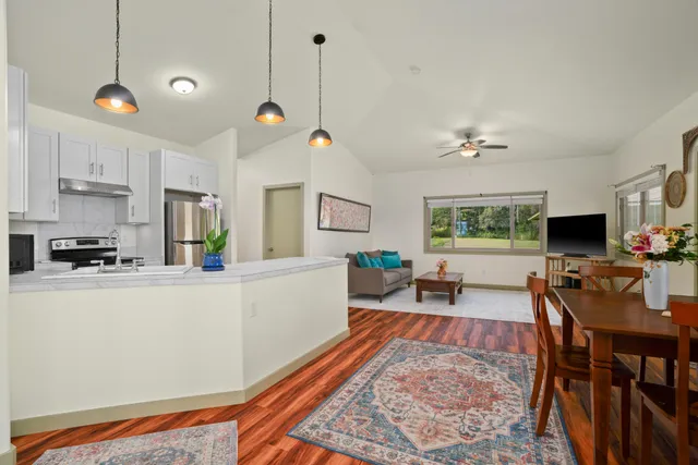 a kitchen with stainless steel appliances granite countertop a refrigerator a sink dishwasher a dining table and chairs with wooden floor