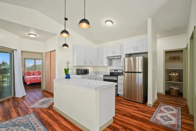 a kitchen that has a refrigerator a stove and a wooden floor
