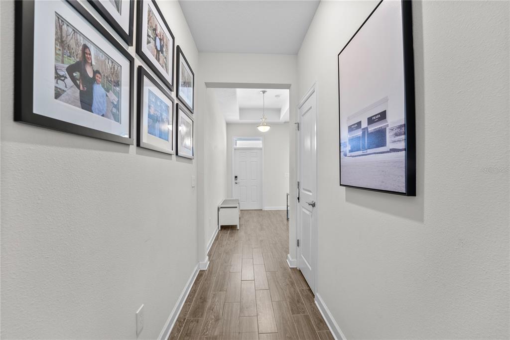 2926 Wordsmith Road Kissimmee, FL 34746 - Photo 4 of 42 a view of a hallway with wooden floor and paintings on the wall