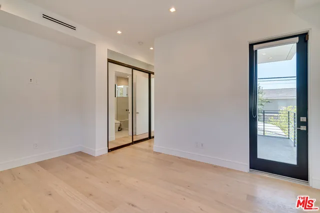 a view of a hallway with wooden floor and a bathroom