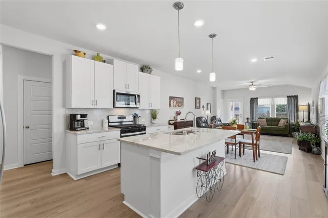 a open kitchen with cabinets a sink a stove a dining table and chairs