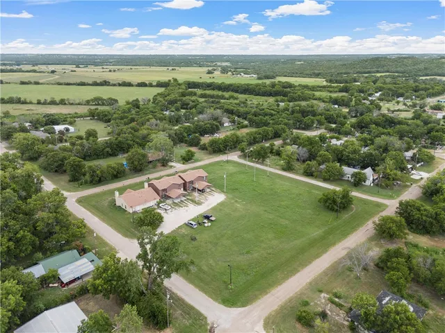 an aerial view of residential houses with outdoor space and trees