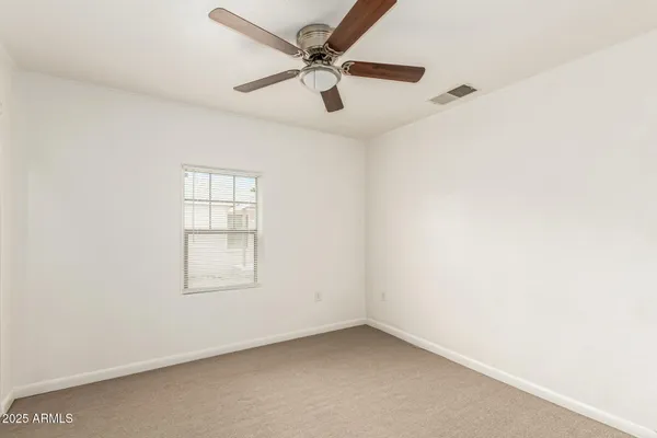 an empty room with windows and ceiling fan