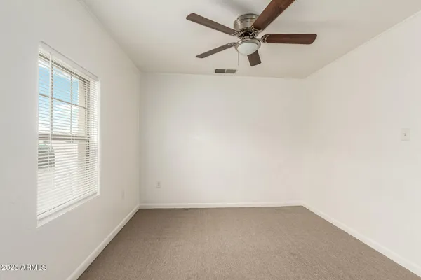 an empty room with a window and a fan