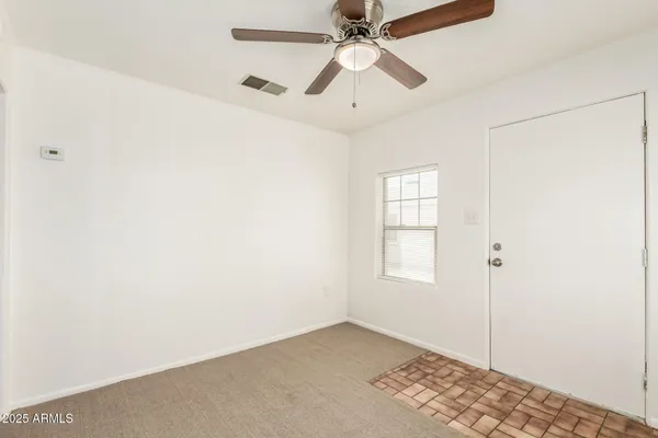an empty room with windows and fan