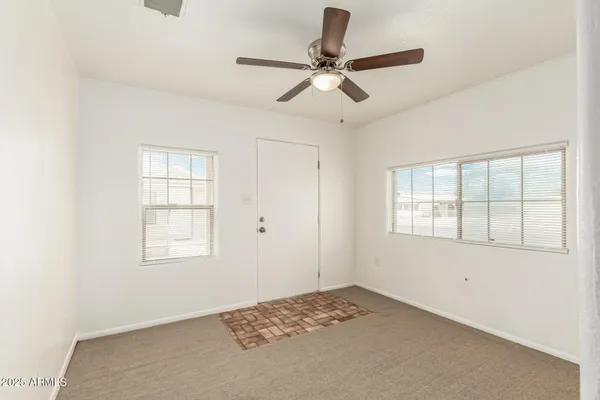 an empty room with a window and a fan