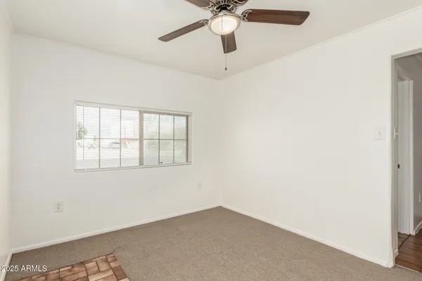 an empty room with a window and a fan