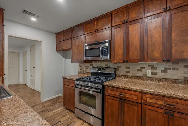 a kitchen with stainless steel appliances granite countertop a stove a microwave and a sink