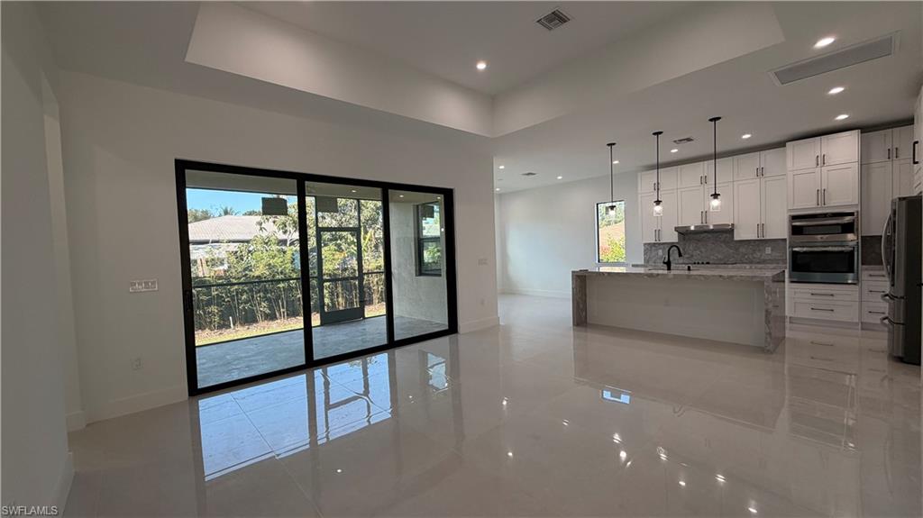 4710 Acadia Lane Naples, FL 34112 - Photo 2 of 10 a living room with stainless steel appliances furniture large windows and a kitchen view
