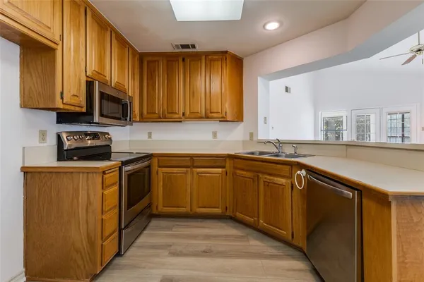 a kitchen with stainless steel appliances granite countertop wooden cabinets a stove top oven a sink and dishwasher