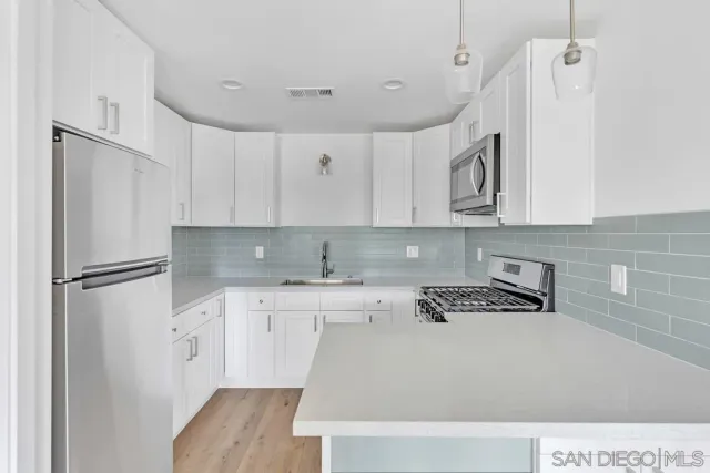 a large white kitchen with kitchen island white cabinets and stainless steel appliances