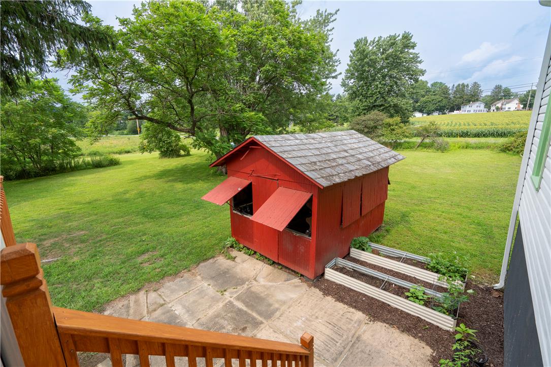 665 Point Phillips Road Bath, PA 18014 - Photo 51 of 73 A charming red outbuilding with raised garden beds sits amidst a verdant landscape.