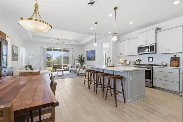 a kitchen with stainless steel appliances granite countertop a table chairs sink and cabinets