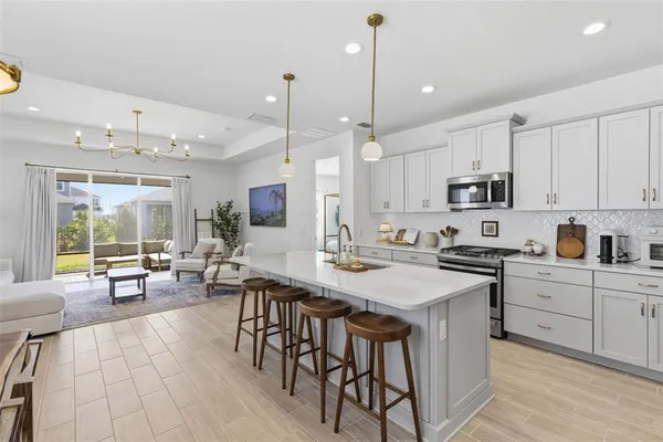 a kitchen with stainless steel appliances kitchen island granite countertop a refrigerator a sink dishwasher a stove a dining table and chairs with wooden floor