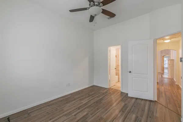 a view of empty room with wooden floor and ceiling fan