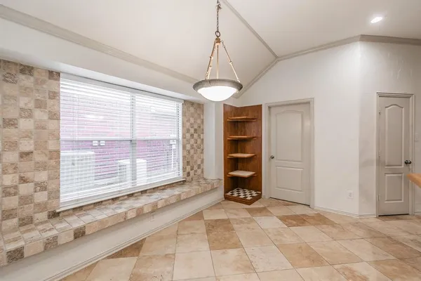 a view of an empty room with a window and kitchen view