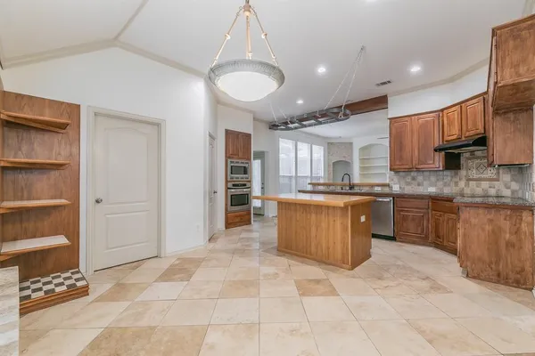 a large kitchen with stainless steel appliances kitchen island granite countertop a refrigerator and a sink