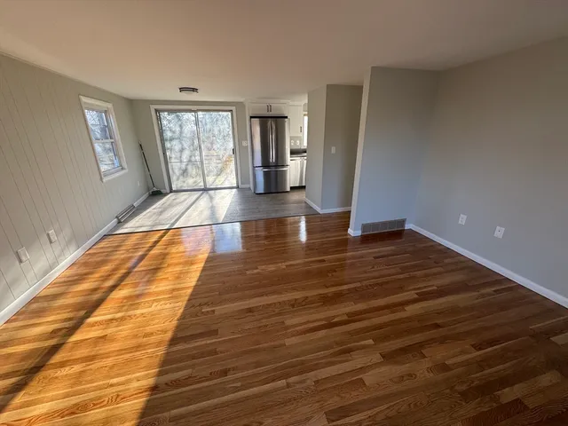 a view of empty room with window and wooden floor
