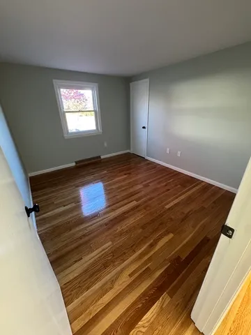 a view of empty room with window and wooden floor