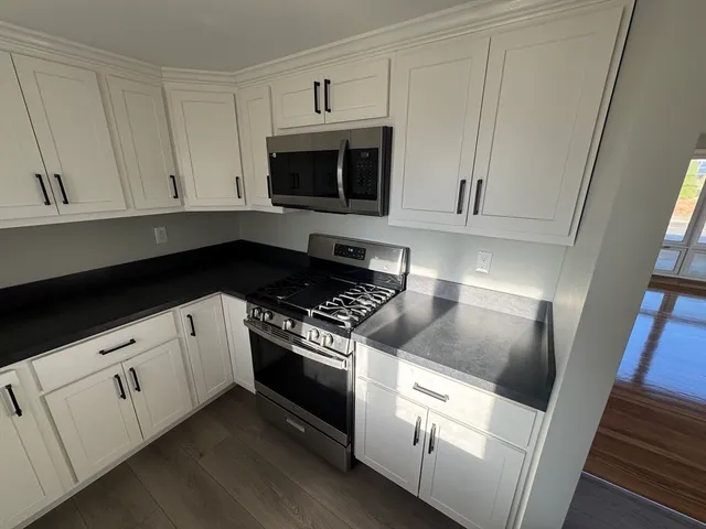 a kitchen with white cabinets and appliances