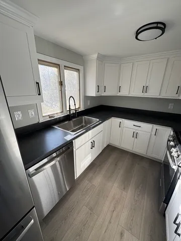 a kitchen with granite countertop a sink a stove and cabinets
