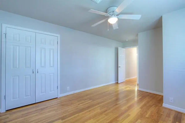 an empty room with wooden floor fan and windows