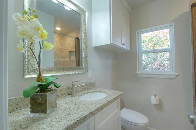 a bathroom with a granite countertop sink a toilet and with mirror