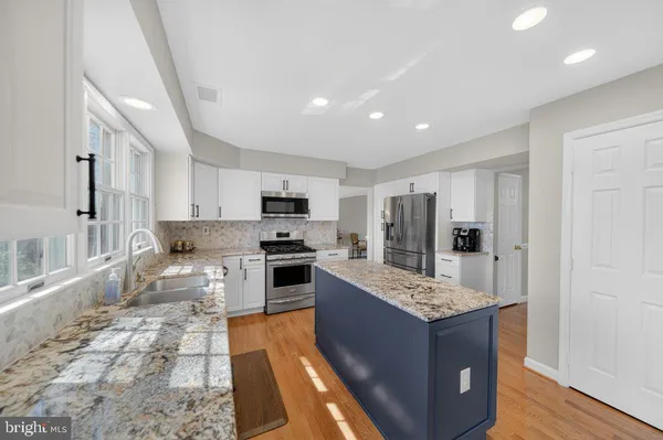 a large kitchen with stainless steel appliances kitchen island granite countertop a refrigerator and a stove top oven