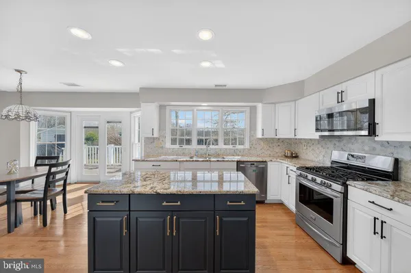 a kitchen with granite countertop a stove top oven a sink a dining table and chairs