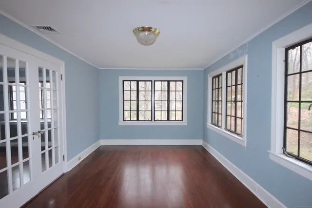 a view of an empty room with wooden floor and a window