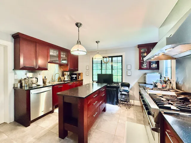 a kitchen with stainless steel appliances granite countertop a stove top oven a sink dishwasher a dining table and chairs with wooden floor