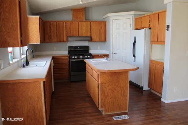 a kitchen with stainless steel appliances a refrigerator a sink a stove and wooden floor